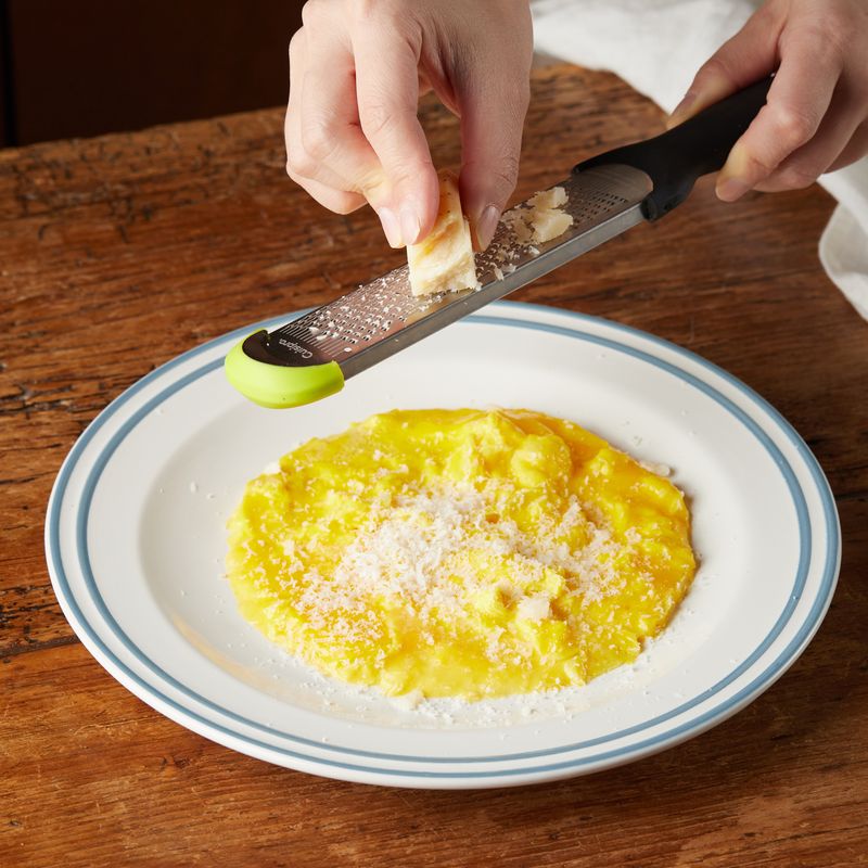 넓은 접시에 달걀을 놓고 파마산 치즈를 갈아서 뿌린 후 볶아둔 버섯을 넣고 반으로 접어주세요.