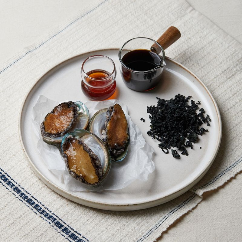 전복미역국을 위한 재료 이미지로 전복,건미역,멸치육수,국간장,참기름 등으로 구성 되어있습니다.