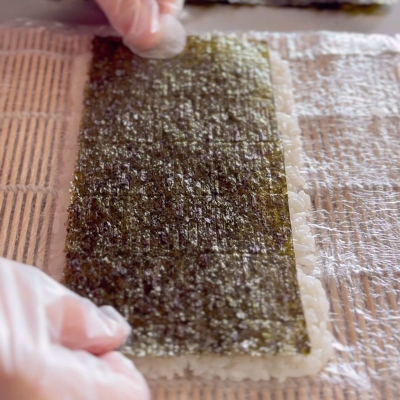밥 위에 김, 크래미, 오이 순으로 올려준 뒤 김발을 사용해 단단히 말아 롤 김밥을 만들어 주세요.