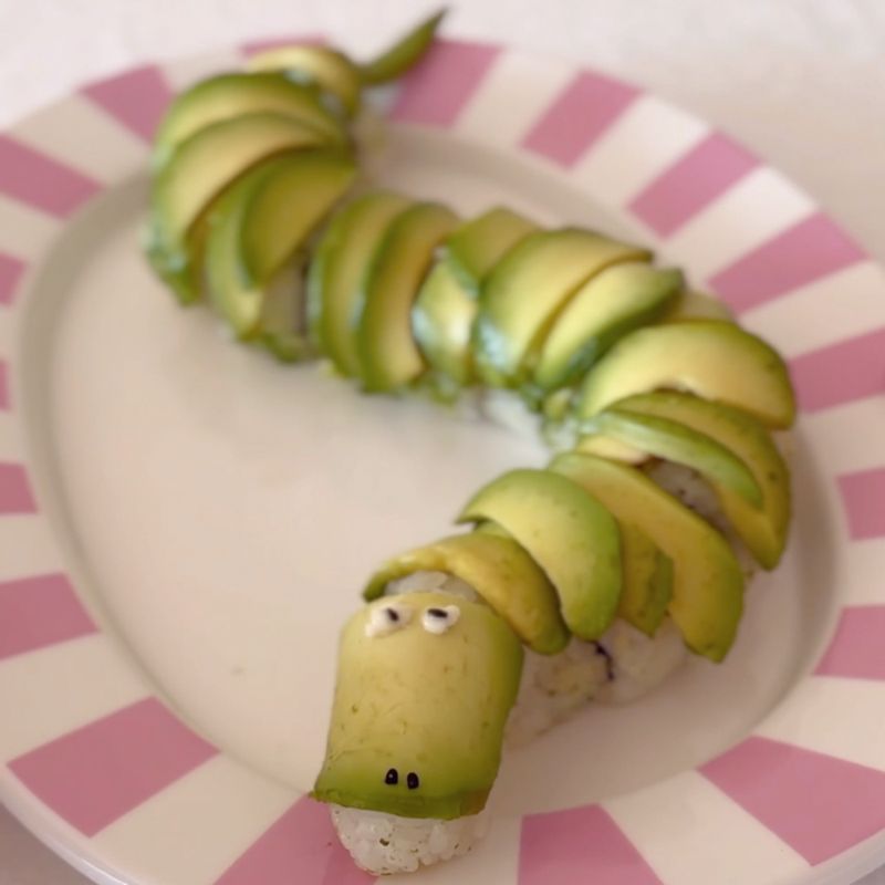 롤 김밥을 깔끔하게 썰어주고 접시에 용 모양으로 구불구불 배치해 주세요. 남은 밥과 아보카도로 용의 머리를 만들고 마요네즈를 콕 찍어 눈알을, 검은깨로 눈동자를 만들어주세요.