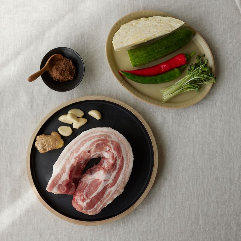 마늘 수육을 위한 재료 이미지로 돼지고기(통삼겹살),양배추,오이,적양파,무순 등으로 구성 되어있습니다.