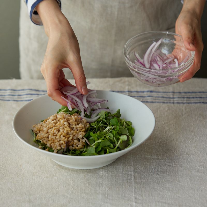 어린잎 채소를 바닥에 깔고 보리귀리밥을 담고 적양파, 새우, 베이컨, 아보카도를 보기 좋게 올려 주세요.