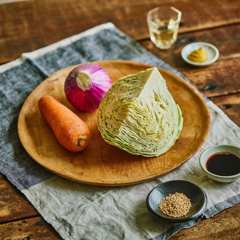 양배추 냉채 샐러드 을 위한 재료 이미지로 양배추,당근,적양파,통깨 등으로 구성 되어있습니다.