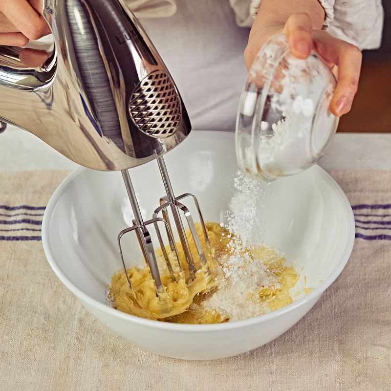 버터와 슈가파우더를 넣고 핸드믹서 거품기를 저속으로 돌려, 가루가 보이지 않을 때 까지 섞어주세요. 소금, 달걀노른자 1개, 바닐라 익스트랙을 넣고 핸드믹서 거품기로 30초간 섞어주세요.