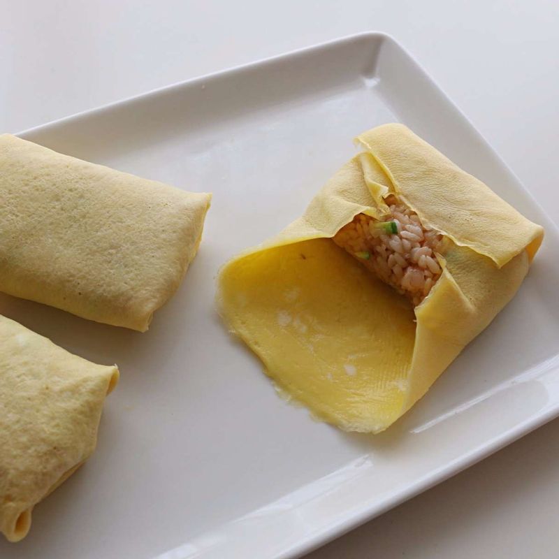 지단에 새우볶음밥을 넣고 양쪽을 접어 돌돌 말아주세요.