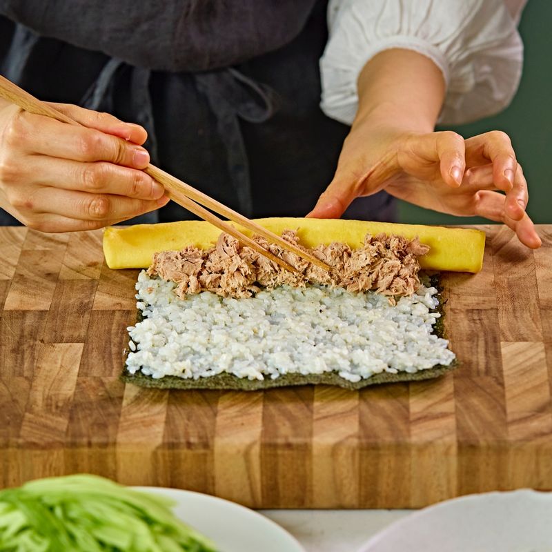 김 위에 밥을 얇게 고르게 편 후 달걀말이, 참치, 묵은지, 오이,를 올려 김밥을 말아 주세요
(tip. 김의 거친면이 위로 올라오게 해주세요)
(tip. 김 끝부분에 참기름을 발라주세요)
(tip. 앞쪽 끝부분을 잡고 살살 눌러 가며 말아주세요. 너무 꾹 누르면 속재료의 물기가 빠져나올 수 있어요)