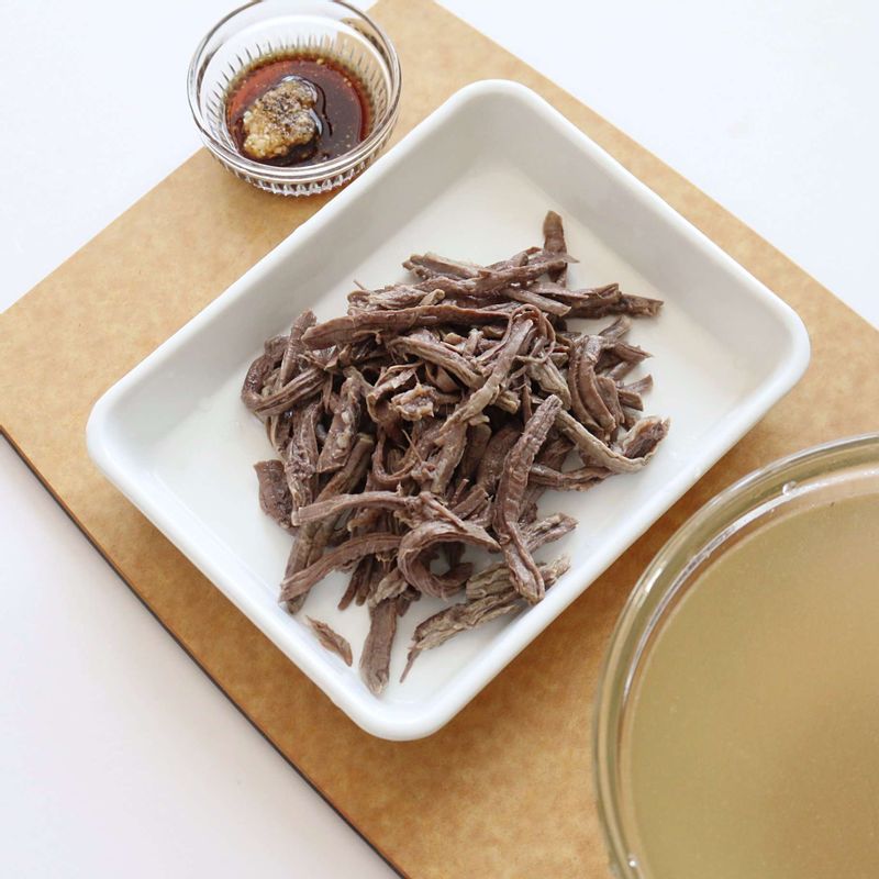 삶은 쇠고기는 결대로 찢은 후 밑간 재료를 넣어 밑간을 하고, 고기육수는 체에 걸러주세요.