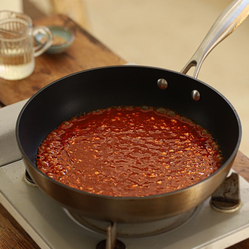 달군 팬에 식용유를 두르고 중약불에서 양념재료를 넣은 후, 끓어오르면 약한불로 줄여 오징어채를 넣어주세요.