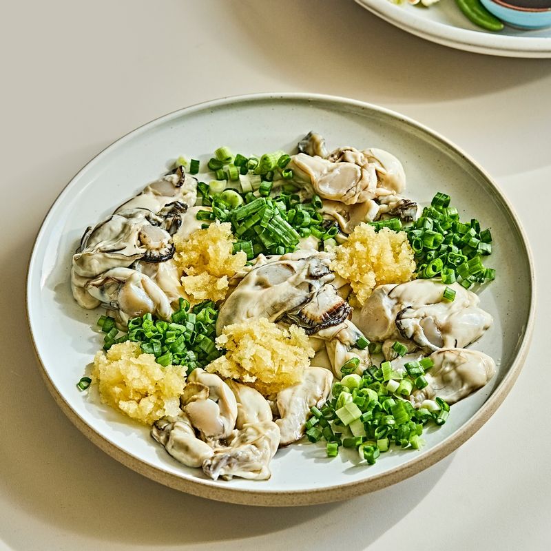 굴을 담은 그릇에 쪽파와 청양고추, 다진 마늘을 넣어주세요.