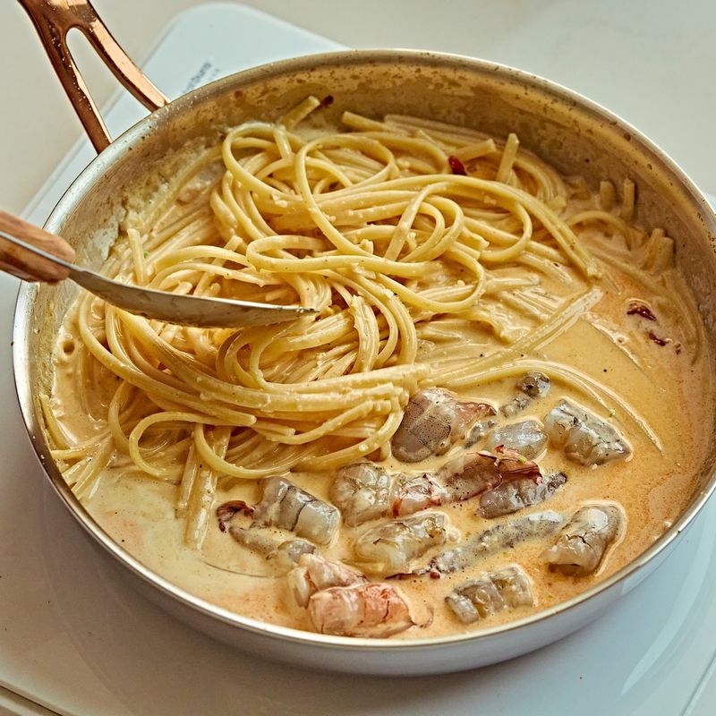 삶은 면과 손질한 새우를 넣고 빠르게 섞어 만테까레를 해 주세요.
(tip.'만테까레(Mantecare)'는 이탈리아어로 파스타나 릿소통에서 물과 기름(올리브 오일 등)을 파스타 면의 전분과 함께 섞어 크리미하고 녹진한 소스를 만드는 유화 과정을 말해요)