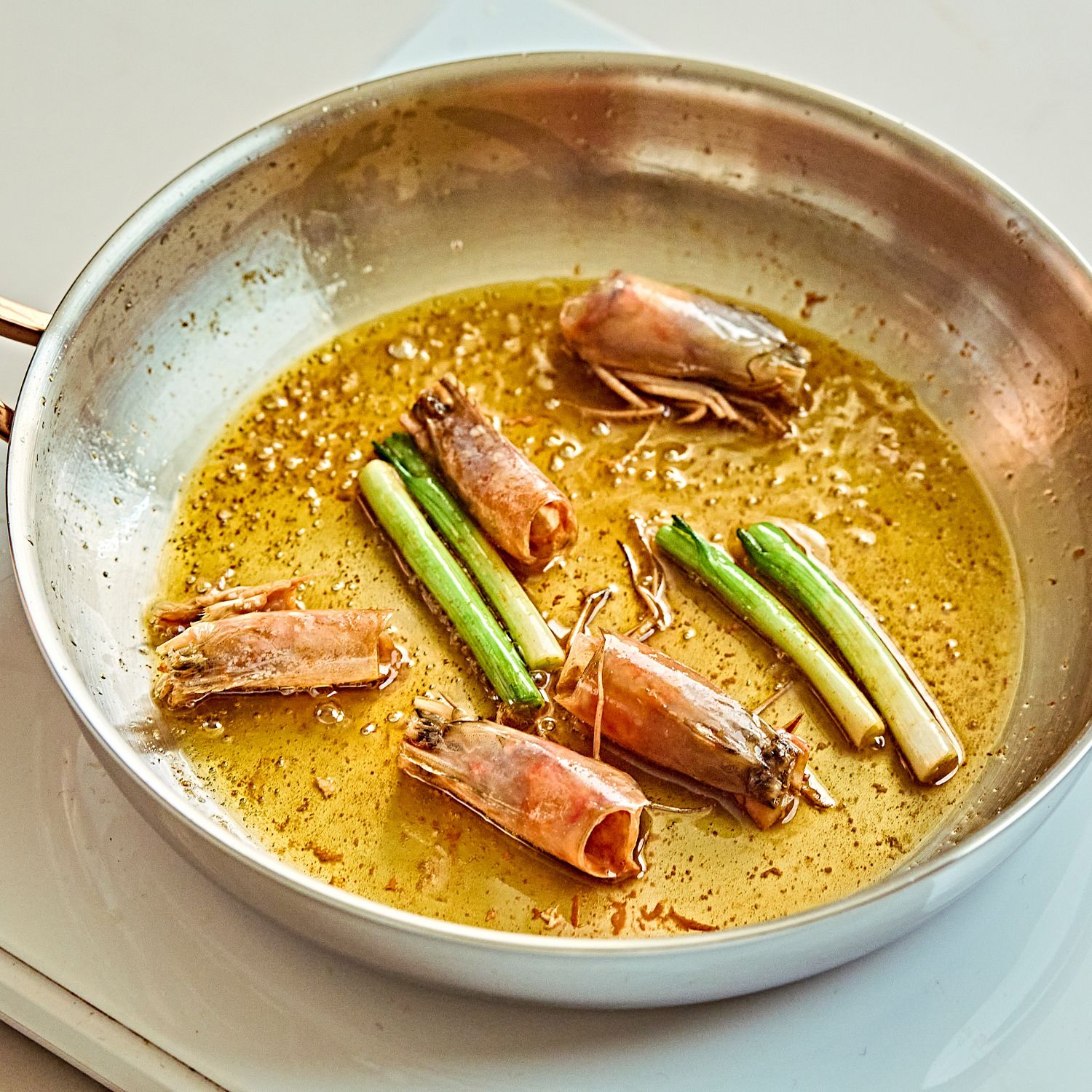 달군 팬에 올리브오일을 두르고 새우 머리와 쪽파 흰부분을 넣어 약불에서 천천히 향을 내주세요.