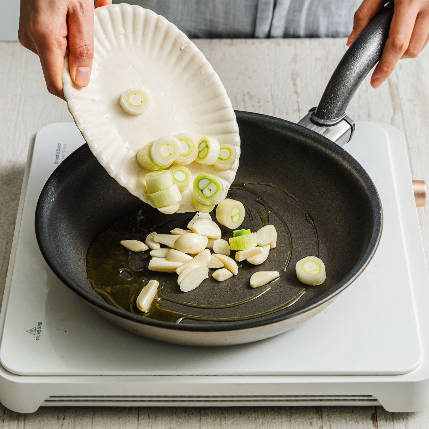 팬에 마늘과 대파를 올린 뒤 참백합을 고르게 펼쳐 담아주세요. 청주를 부어주세요.
