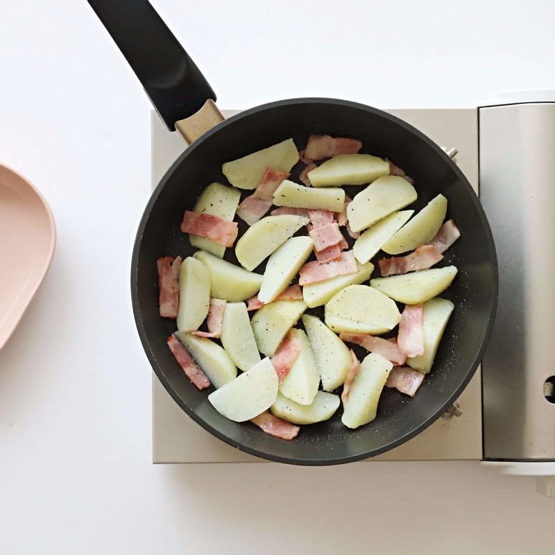 팬에 약간의 올리브유를 두른 후 베이컨과 삶은 감자를 넣고, 소금과 후추를 약간씩 넣어 2분 정도 볶아주세요.
