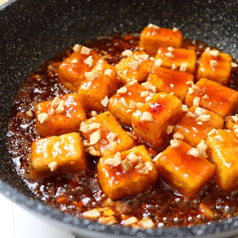 팬에 양념 재료를 넣고 2분정도 바글바글 끓이다가, 양념의 농도가 걸쭉해지면 튀겨 놓은 두부와 다진 땅콩, 호두를 넣고 섞어주세요.