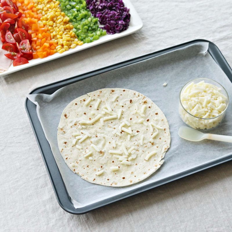 토르티야에 피자치즈 한줌을 올리고, 그 위에 토르티야 한 장을 더 올린 후 토마토소스를 골고루 펴서 발라주세요.