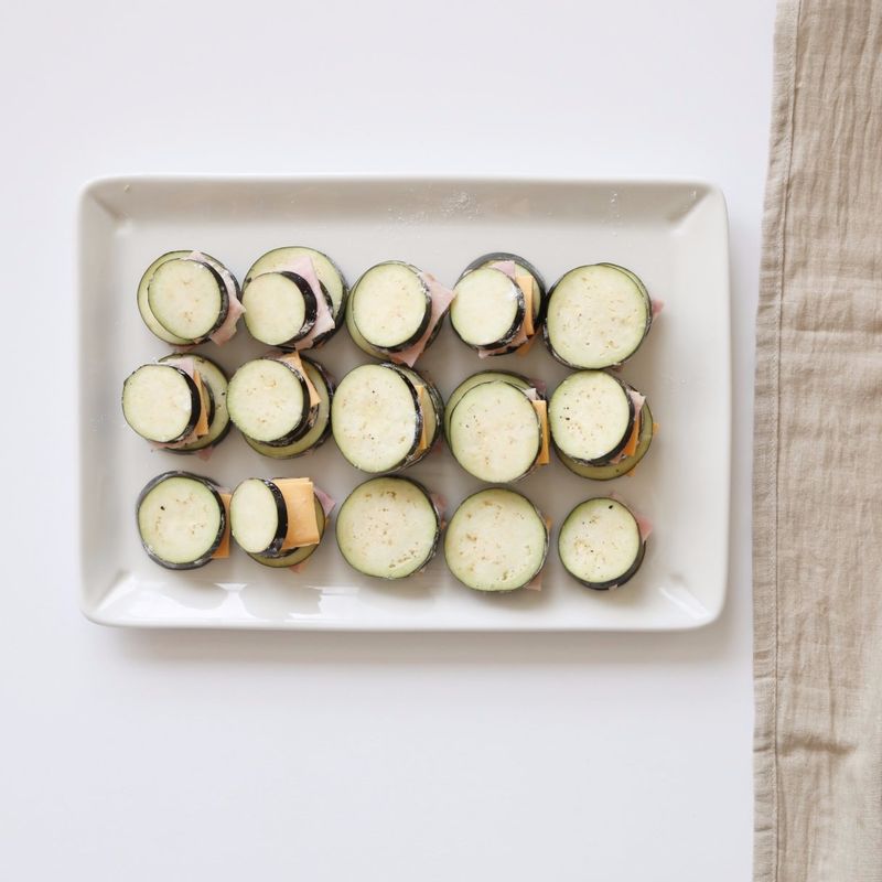 가지의 칼집 사이에 밀가루를 뿌리고 털어 낸 후, 치즈와 베이컨을 넣어주세요.