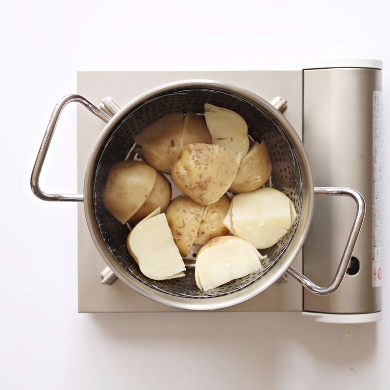 감자를 껍질 채 씻어 4등분하고, 김이 오른 찜통에 감자가 포슬거리도록 20분 정도 쪄주세요.
찐감자는 껍질을 벗겨 뜨거울 때 볼에 넣어 으깨고, 버터 1큰술과 약간의 소금, 후추를 더해 섞어주세요.