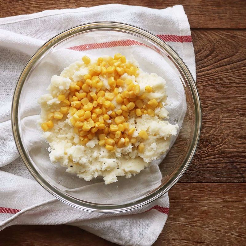 찐감자는 뜨거울 때 볼에 넣어 으깬 후 스위트콘, 밑간 재료, 전분가루를 넣어 섞어주세요.