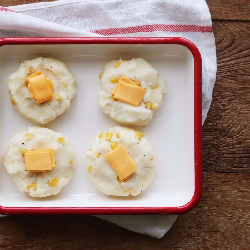 감자 반죽을 한입크기로 떼어내 가운데에 체더치즈를 잘라 올리고, 치즈를 감싸듯 동그랗게 뭉쳐 가운데 부분을 평평하게 만들어 주세요.