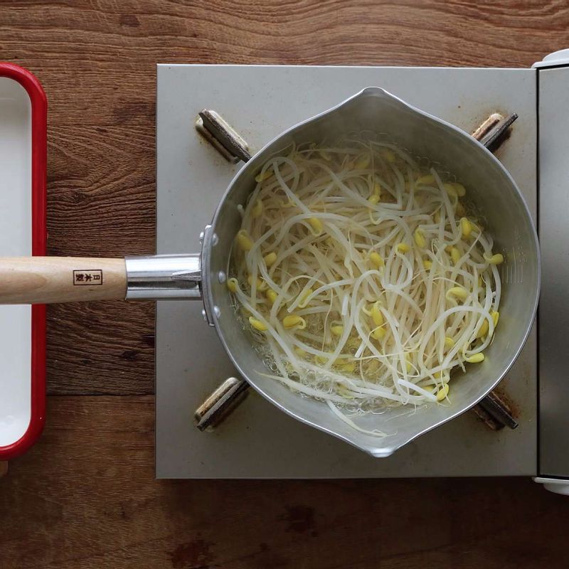 콩나물은 깨끗이 씻어 손질해주세요. 냄비에 물 2컵과 약간의 소금을 넣고, 물이 끓어오르면 콩나물을 넣어 1분 정도 데쳐 식혀주세요.