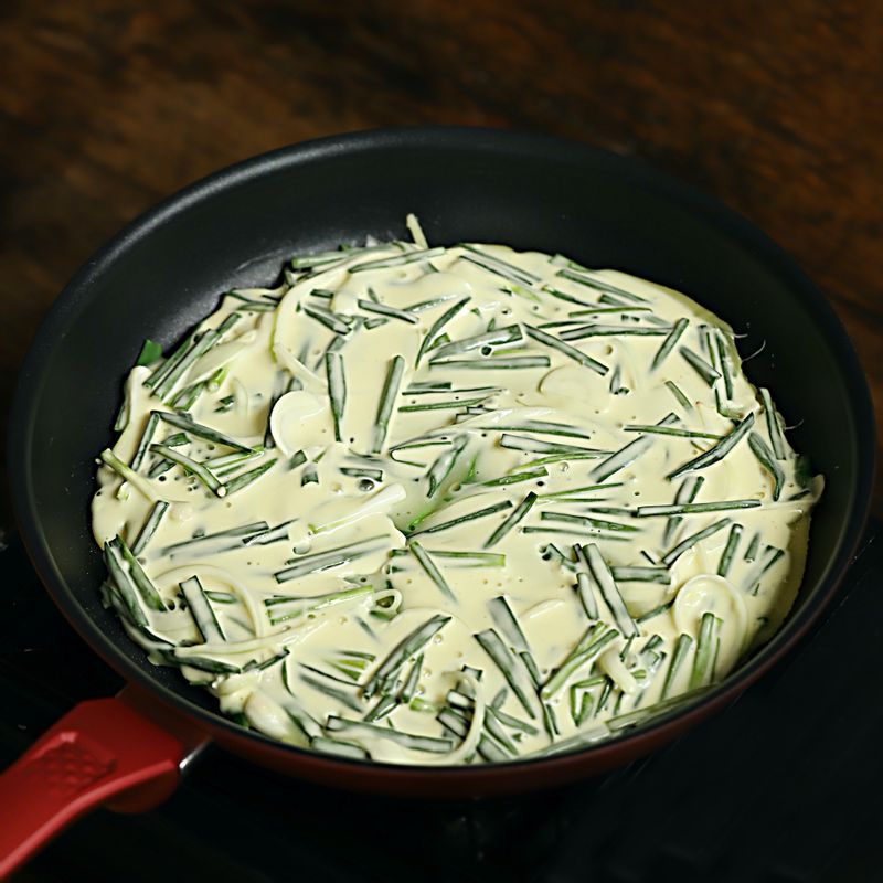 달군 팬에 기름을 두르고 반죽을 넣어 펼치고 양념한 쇠고기를 골고루 나누어 올려주세요. 남은 반죽을 2큰술을 쇠고기 위에 올려 구워주세요.