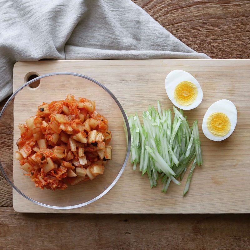 김치는 굵게 다져 양념재료와 섞어주세요. 오이는 채썰고, 삶은달걀은 이등분으로 잘라주세요.