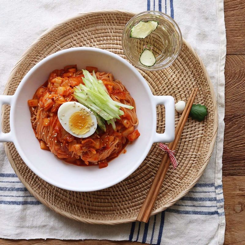 접시에 비빔국수를 담고 삶은 달걀과 오이채, 깨를 올려주세요.