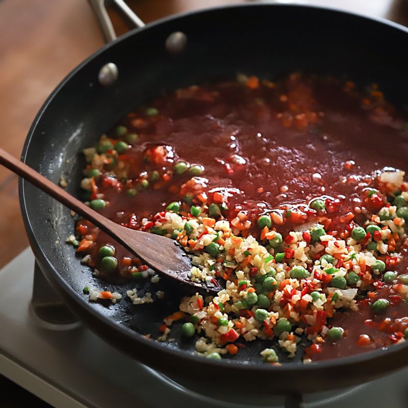 마늘의 향이 올라오면 다진 양파, 당근, 청홍고추, 완두콩 순서로 넣어 약간 볶다가 불을 줄이고 소스 재료를 모두 넣어 조려주세요.