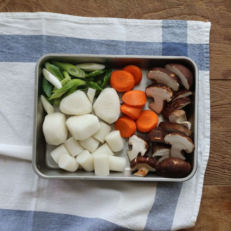 무와 당근은 한입크기로 자른 후 모서리를 둥글게 다듬고, 가래떡은 먹기 좋은 크기로 잘라주세요. 표고버섯은 3등분으로 자르고 청양고추와 대파는 어슷하게 썰어주세요.