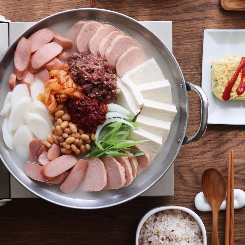 냄비에 햄, 소시지, 대파, 김치, 양파, 두부, 다진쇠고기, 베이크드빈스를 돌려 담고 양념재료를 섞어 올린 후 사골육수를 부어 5분 정도 끓여주세요.