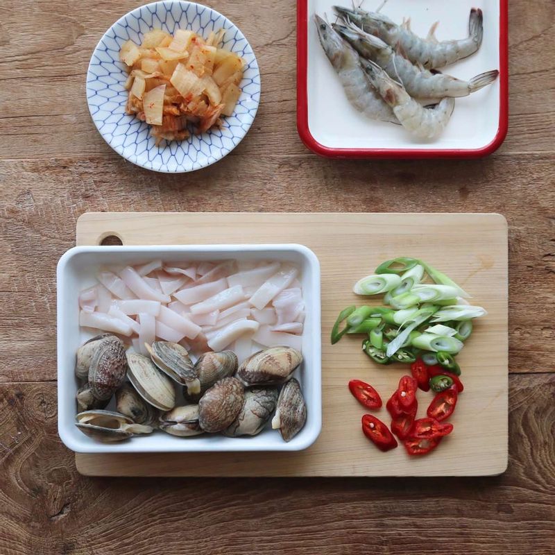 바지락조개는 소금물에 담가 해감하고, 오징어는 껍질을 벗겨 먹기 좋게 썰어주세요. 새우는 수염을 자르고 나무 꼬치로 내장을 빼주세요. 김치는 잘게 썰고, 홍고추와 고추, 대파는 어슷하게 썰어주세요.