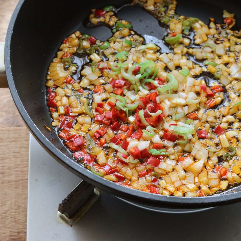달군 팬에 고추기름을 두르고 대파, 홍고추, 양파를 넣어 볶아주세요. 다진 돼지고기와 양념재료를 넣고 볶다가 돼지고기가 익으면 청고추를 넣고, 물을 부어 2분 정도 더 끓여주세요.