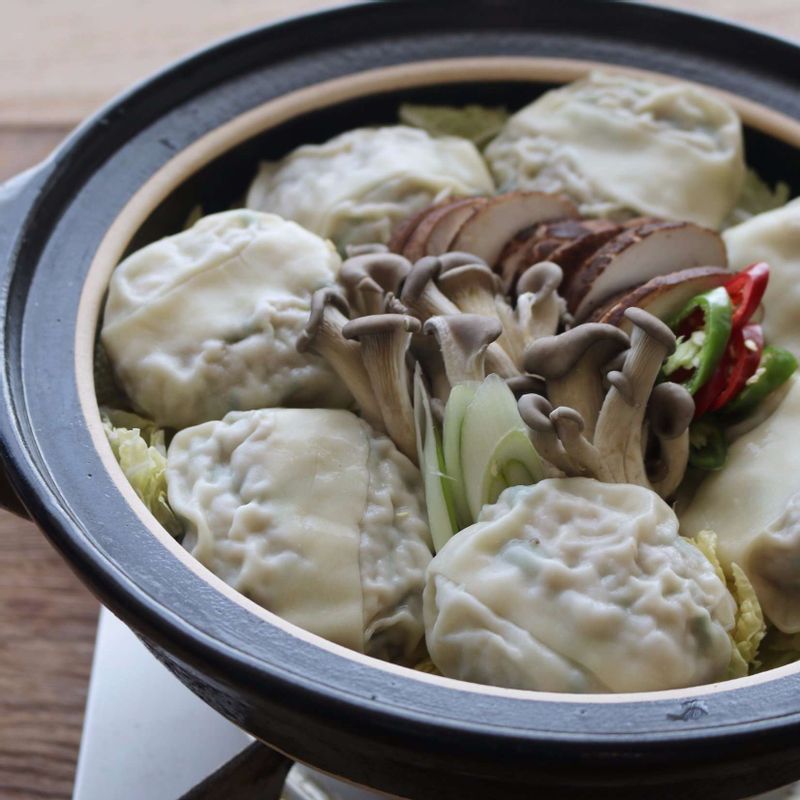 전골냄비 바닥에 배추를 깔고, 만두를 돌려 담은 후 가운데에 표고버섯, 느타리버섯, 대파, 고추를 담아주세요.