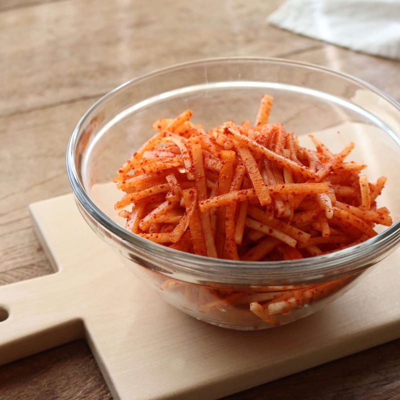 볼에 무채와 고춧가루를 넣고 버무려 10분 정도 고춧가루물을 들여주세요.