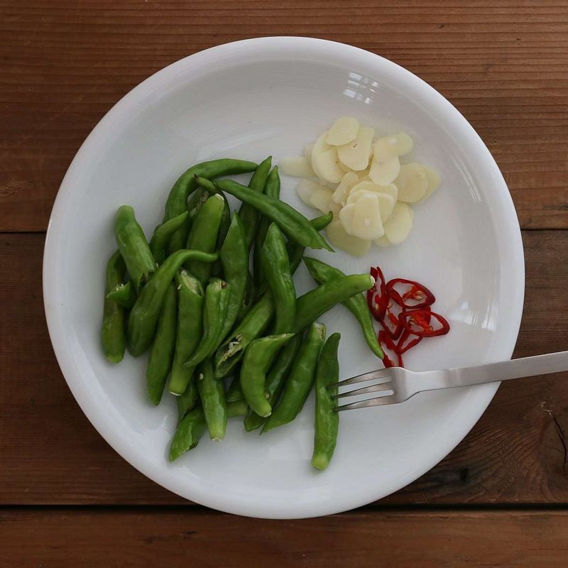 꽈리고추는 꼭지를 떼고 씻은 후 이등분해주세요. 마늘은 편으로 썰고 홍고추는 어슷하게 썰어주세요.