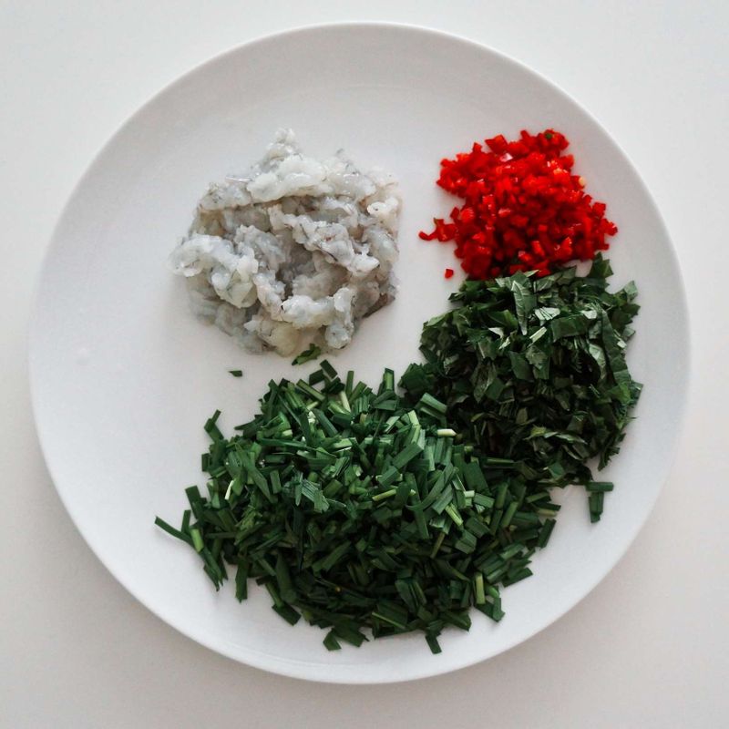 부추는 1cm 길이로 썰고, 깻잎은 부추와 같은 크기로 얇게 채를 썰어주세요. 홍고추는 반으로 갈라 씨를 빼고 잘게 다져주시고, 새우는 껍질을 벗긴 후 먹기 좋게 다져주세요.