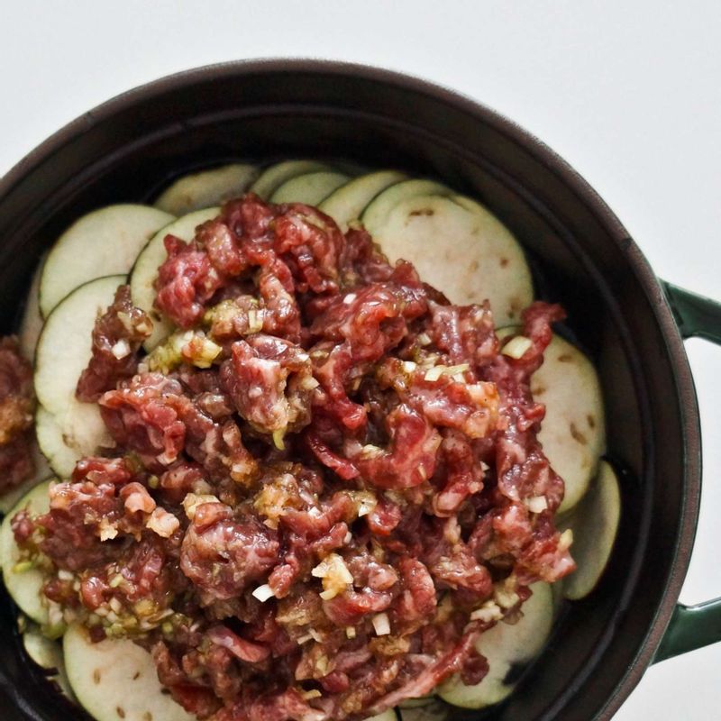 냄비에 참기름을 두르고 STEP1의 쌀과 물 2컵을 넣은 후 STEP3의 가지와 STEP2의 소고기를 얹어 강불에서 끓여주세요.