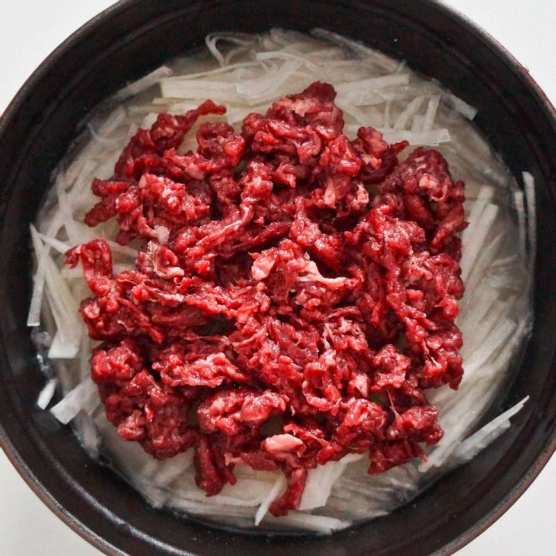 STEP2의 냄비에 STEP1의 무와 소고기를 올린 후 뚜껑을 닫아주세요. 중불에서 끓이다 물이 끓어오르기 시작하면 약불에서 15분 정도 익힌 후 불을 끄고 10분 동안 뜸을 들여주세요.