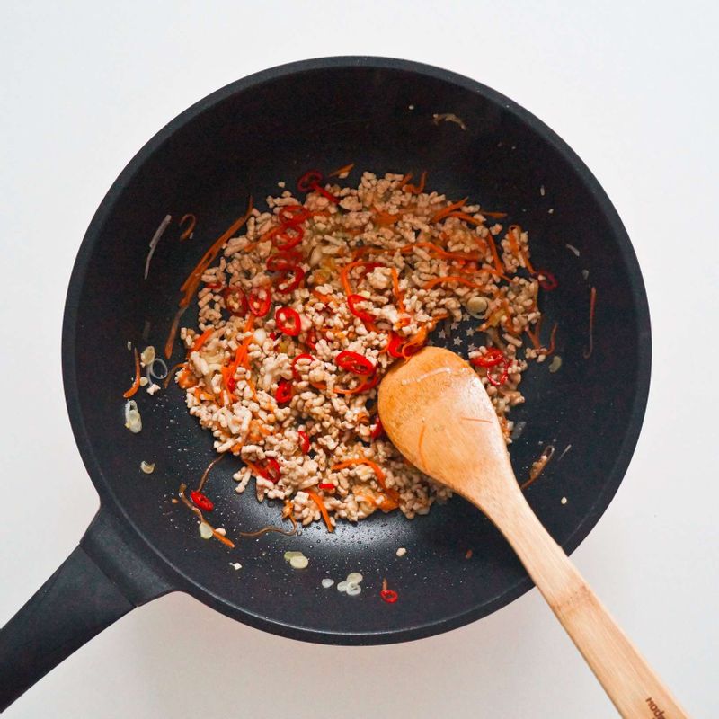 달군 팬에 식용유와 대파를 넣고 볶아 파기름을 만든 후 STEP1의 돼지고기와 STEP2의 당근, 홍고추, 그리고 굴소스, 설탕, 멸치액젓을 넣고 볶아주세요.