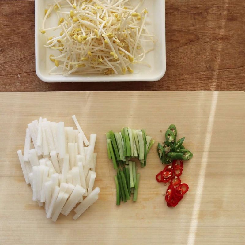 무는 4센치 길이로 굵게 채썰고, 고추는 어슷하게 썰어주세요. 콩나물은 다듬어 깨끗이 씻고 실파는 4센치 길이로 썰어주세요.