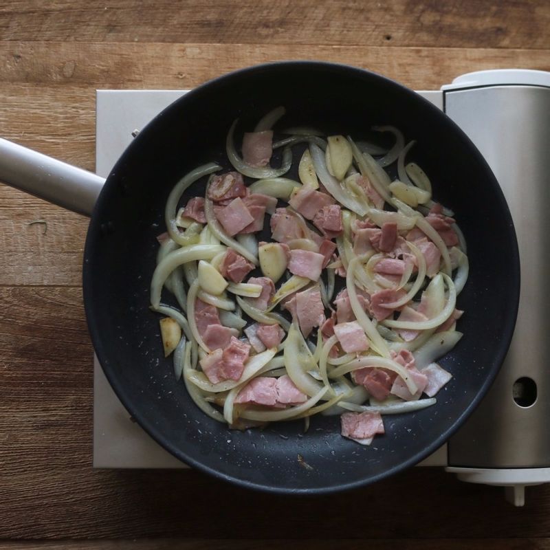 달군 팬에 버터를 넣고 마늘편과 양파, 베이컨을 넣어 2분 정도 볶아주세요.