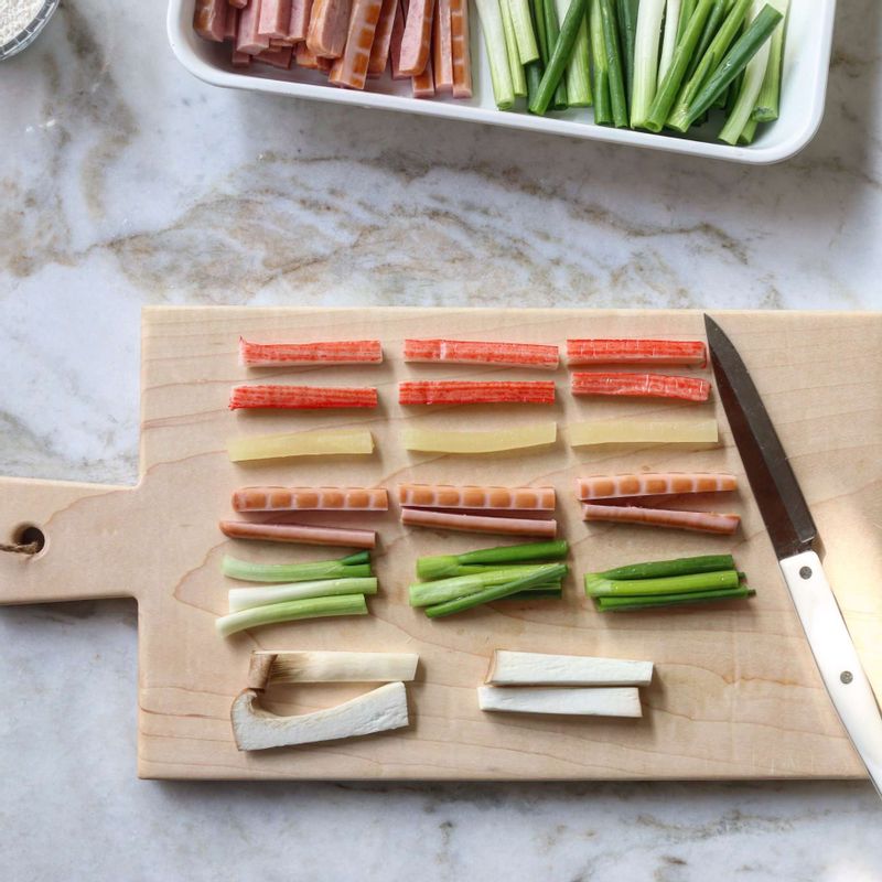 게맛살은 길게 반으로 가른 후 3등분으로 자르고 단무지, 햄, 쪽파를 게맛살 길이로 잘라주세요. 새송이는 밑동을 자르고. 이등분으로 한 후 게맛살 두께로 잘라주세요.