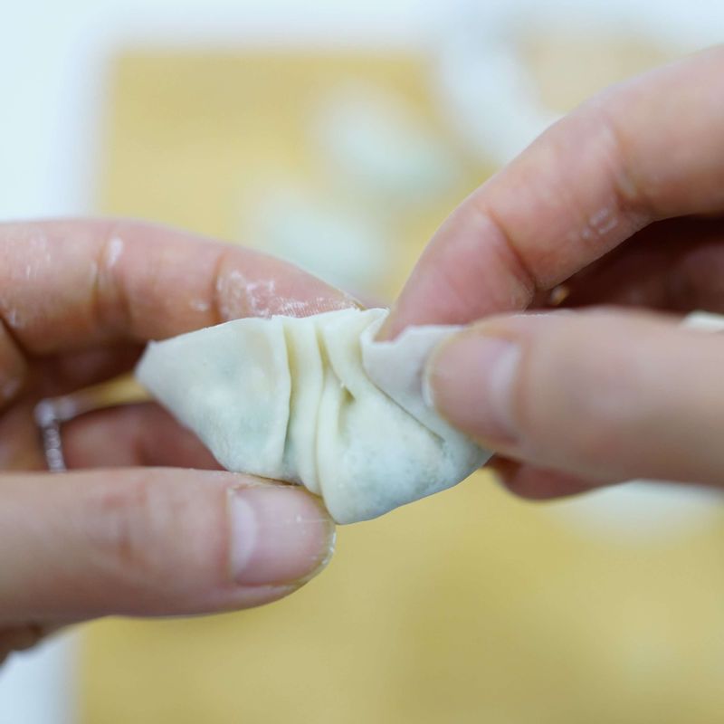 만두 속을 만두피 중앙에 한 숟갈 넣고 반으로 접어 엄지와 검지를 이용해 맞주름을 만들어 주세요. 만두 양 끝을 손끝으로 꼼꼼하게 잡아 반달 모양을 만들어 주세요.