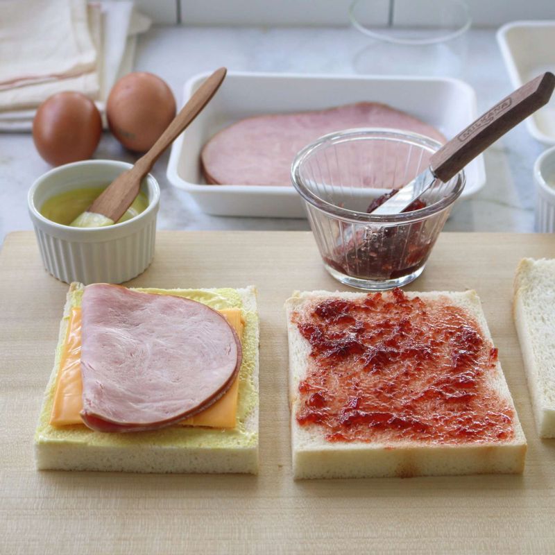 테두리를 자른 식빵 한 면에 허니머스터드를 고루 펴바르고-치즈2장-햄을 올리고, 나머지 한 면에 딸기쨈을 발라 덮은 후 반복해서 허니머스터드 펴바른 식빵-치즈2장-햄-딸기쨈을 한면에 바른 식빵으로 덮어주세요.
