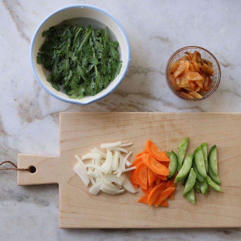 오이와 당근은 길게 반으로 갈라 어슷썰고, 양파는 채썰어주세요. 쑥갓은 씻어 잎만 떼고, 김치는 먹기 좋은 크기로 잘라주세요.