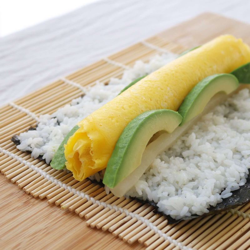 김발 위에 김을 올리고 밥을 고르게 편 후 말아놓은 지단과 아보카도, 단무지를 올리고 김발을 이용해서 돌돌 말아주세요