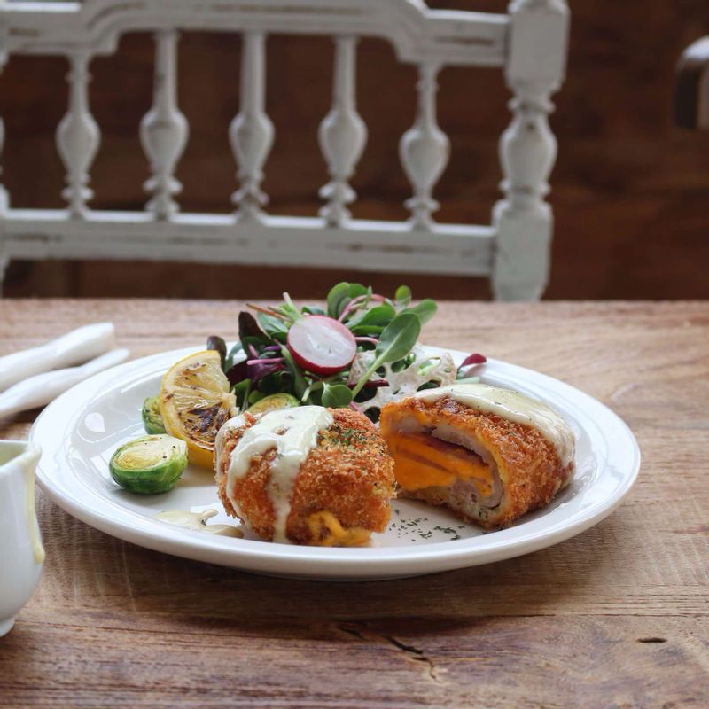 치킨 꼬르동 블루를 먹기 좋게 썰어 접시에 담고, 레몬소스와 샐러드야채를 곁들여 주세요.