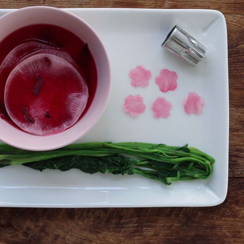 끓는물에 약간의 소금을 넣어 미나리를 살짝 데친 후 찬물에 담갔다가 물기를 제거해주세요. 쌈무 슬라이스는 꽃모양틀로 찍어 비트즙 물에 30분 정도 담가 분홍물을 들여주세요.