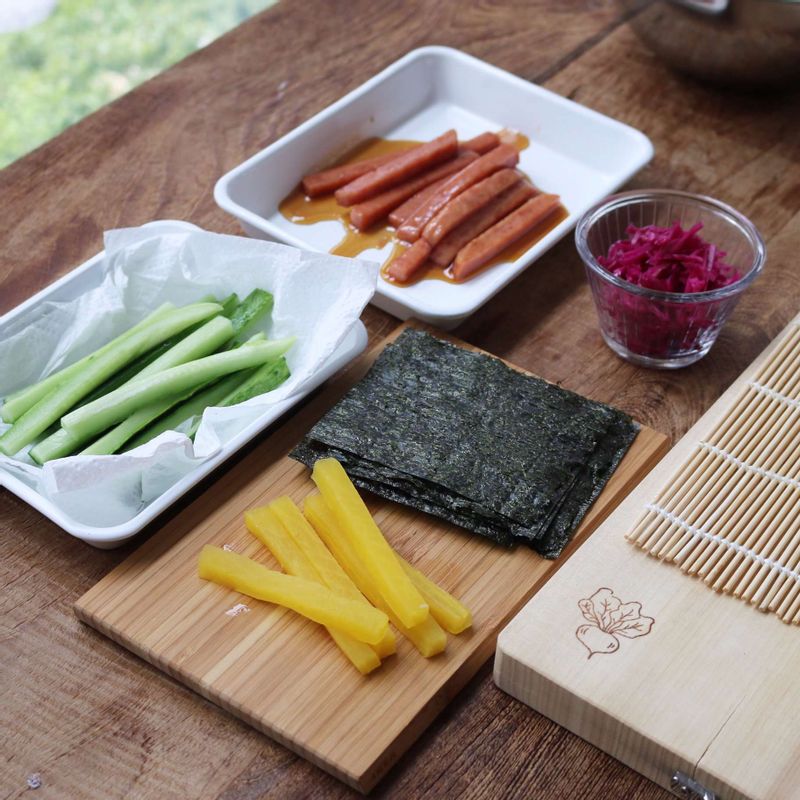 4등분으로 자른 구운 김 위에 밥을 1/4정도 고르게 편 후 오이, 단무지, 스팸, 적채피클을 각각 넣어 돌돌 말아주세요.