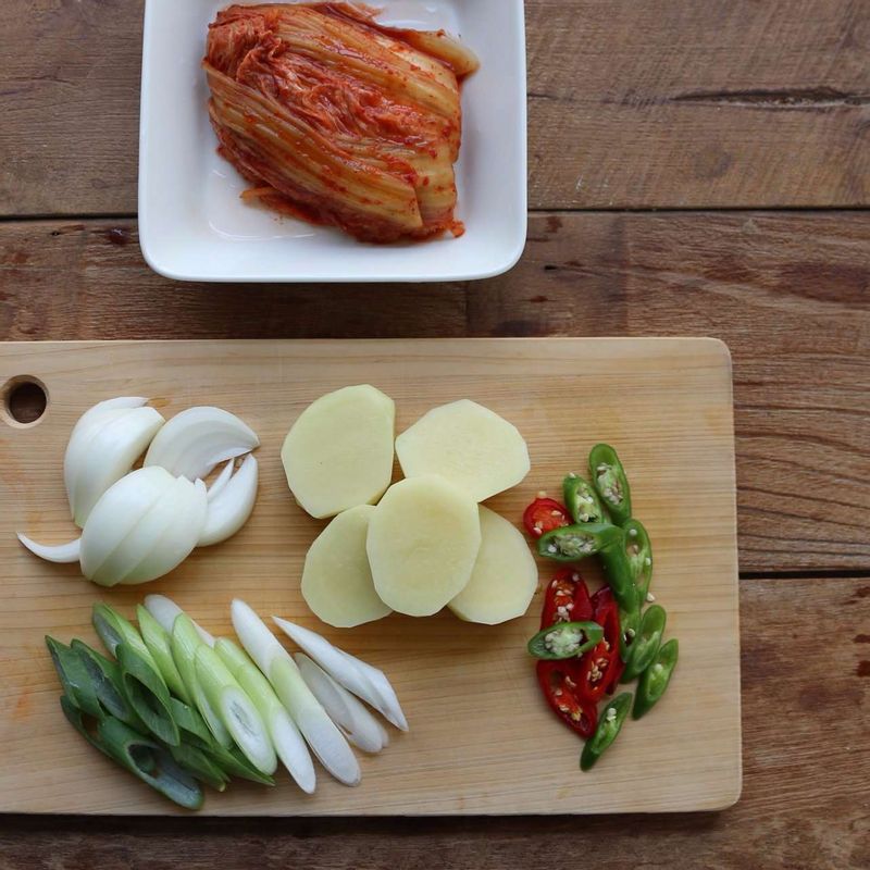 묵은지는 소를 털어내 밑동부분을 잘라내고, 감자는 큼직하게 썰어주세요. 양파는 굵게 채를 썰고 대파, 홍고추, 청양고추는 어슷하게 썰어주세요.